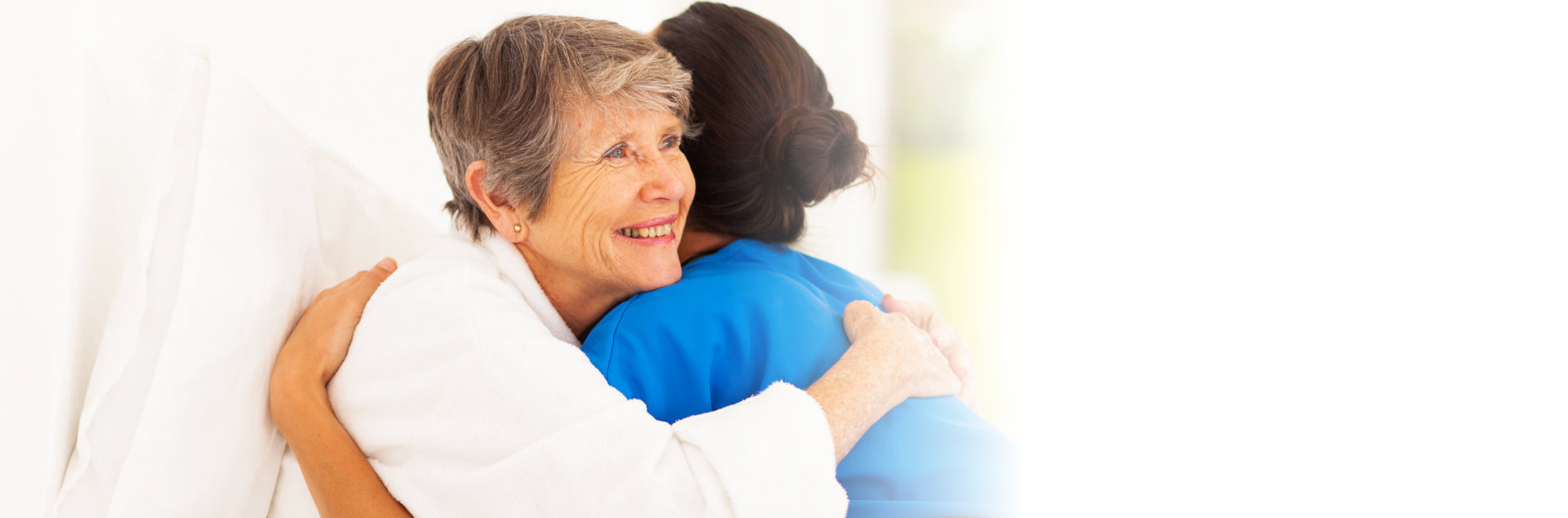 old woman and caregiver hugging each other